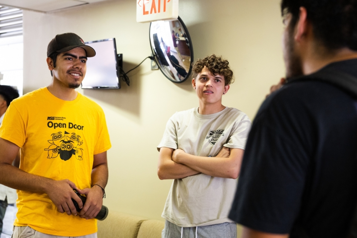 Three student move-in volunteers stand around talking