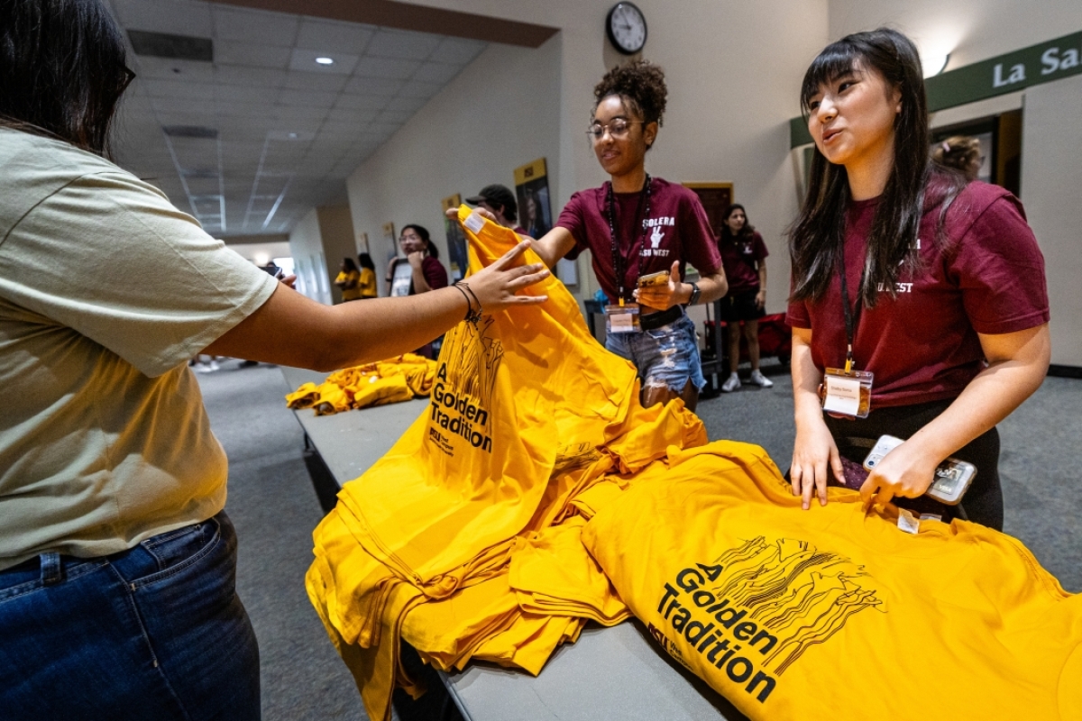 Students handing out gold t-shirts at ASU welcome event