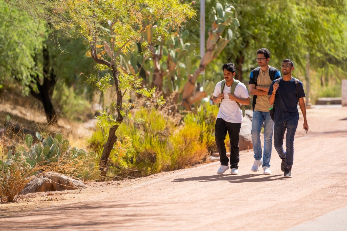 Three students walking on unpaved path on Polytechnic campus