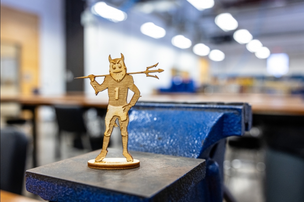 Laser-cut wooden Sparky mascot in a fabrication studio.