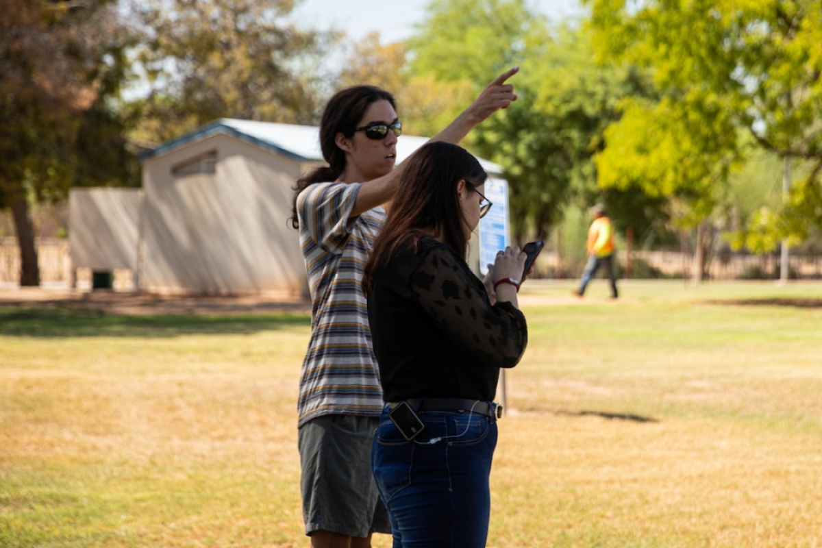 Two ASU students stand in a park and observe their surroundings.