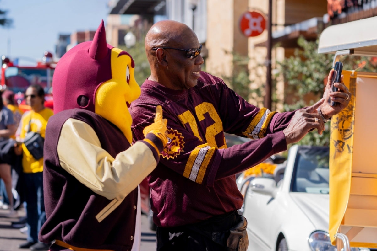 Man taking selfie with Sparky at ASU Homecoming