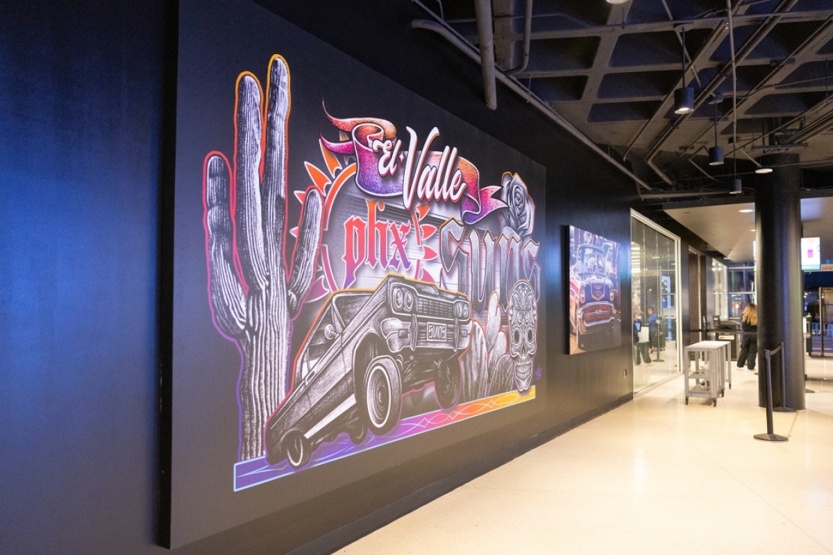 Mural in arena that says El Valle and features saguaros and a lowrider car
