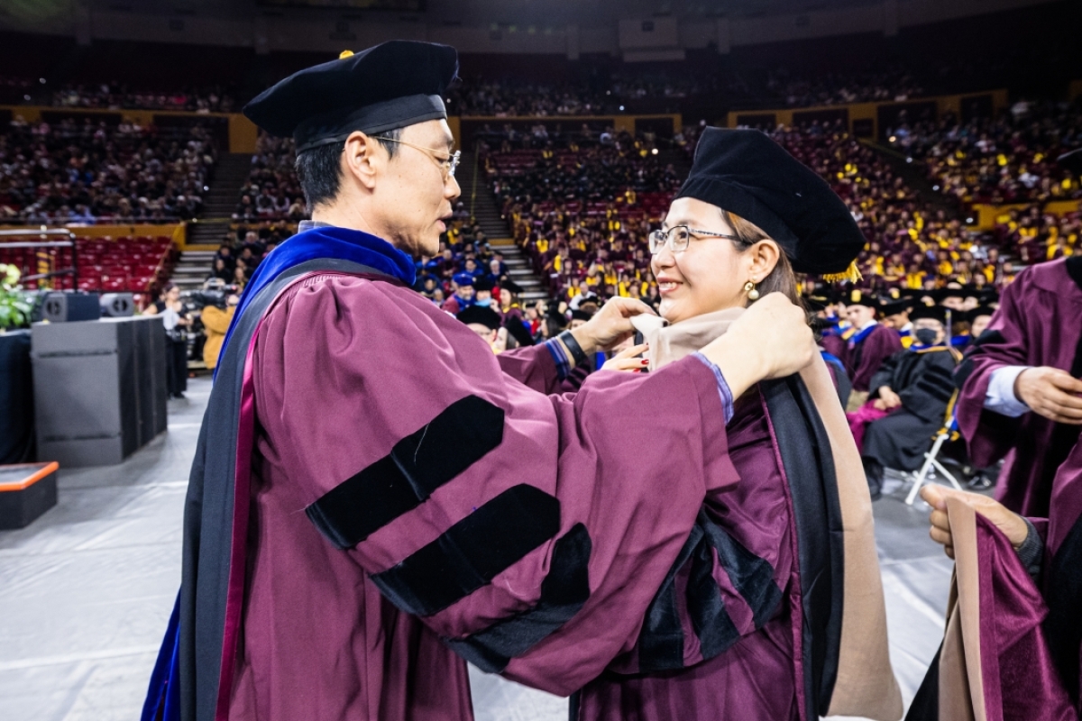 Professor placing graduate hood on student