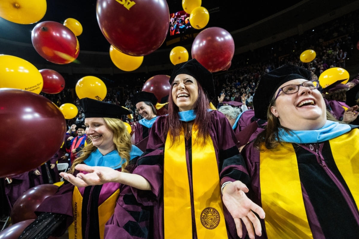 Graduates smiling as balloons drop during commencement