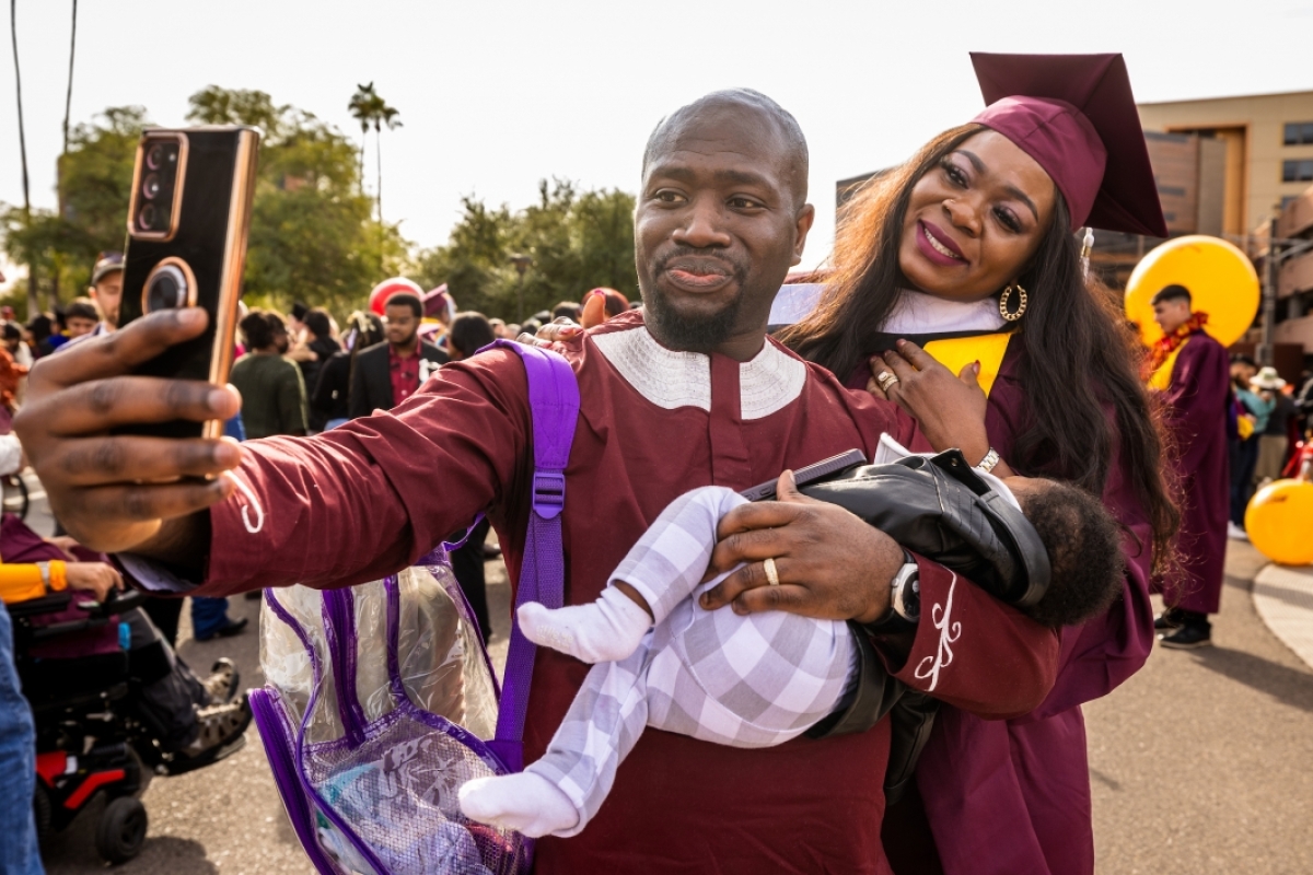 Man taking selfie of himself and wife after graduate commencement