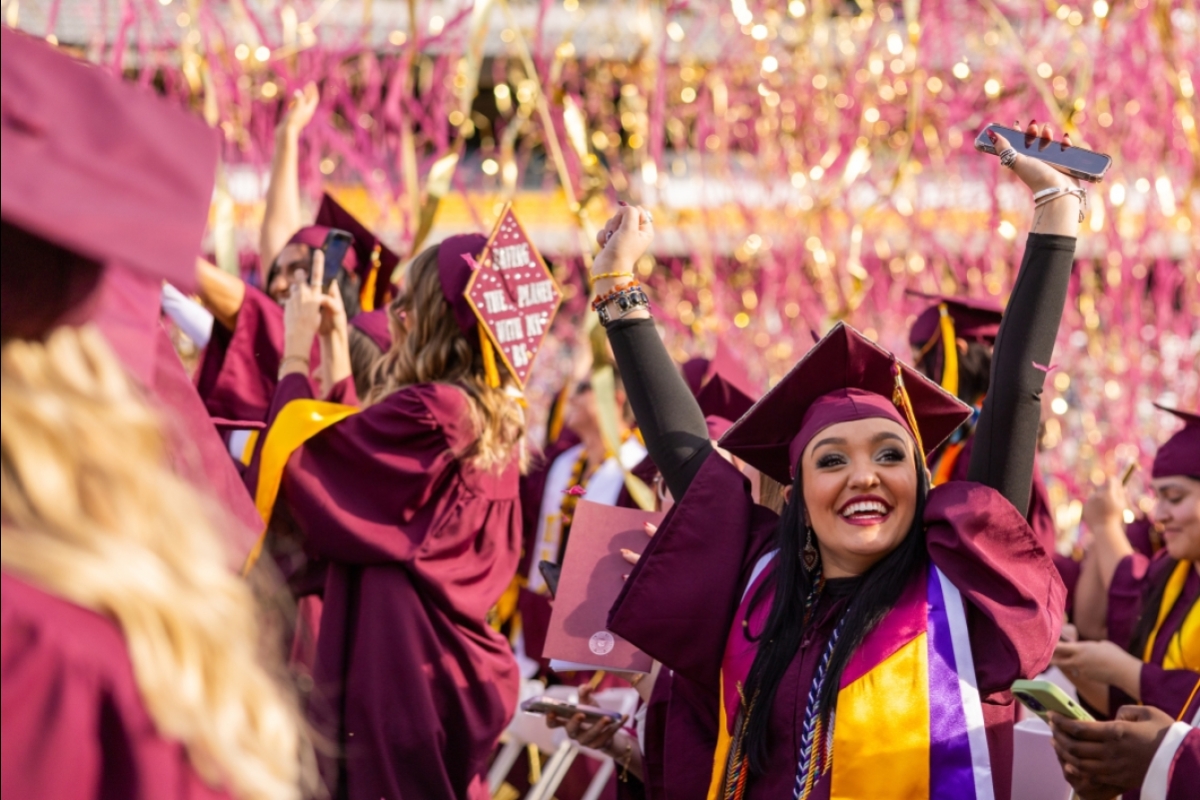 Graduate has arms raised in air as streamers fall down at commencement