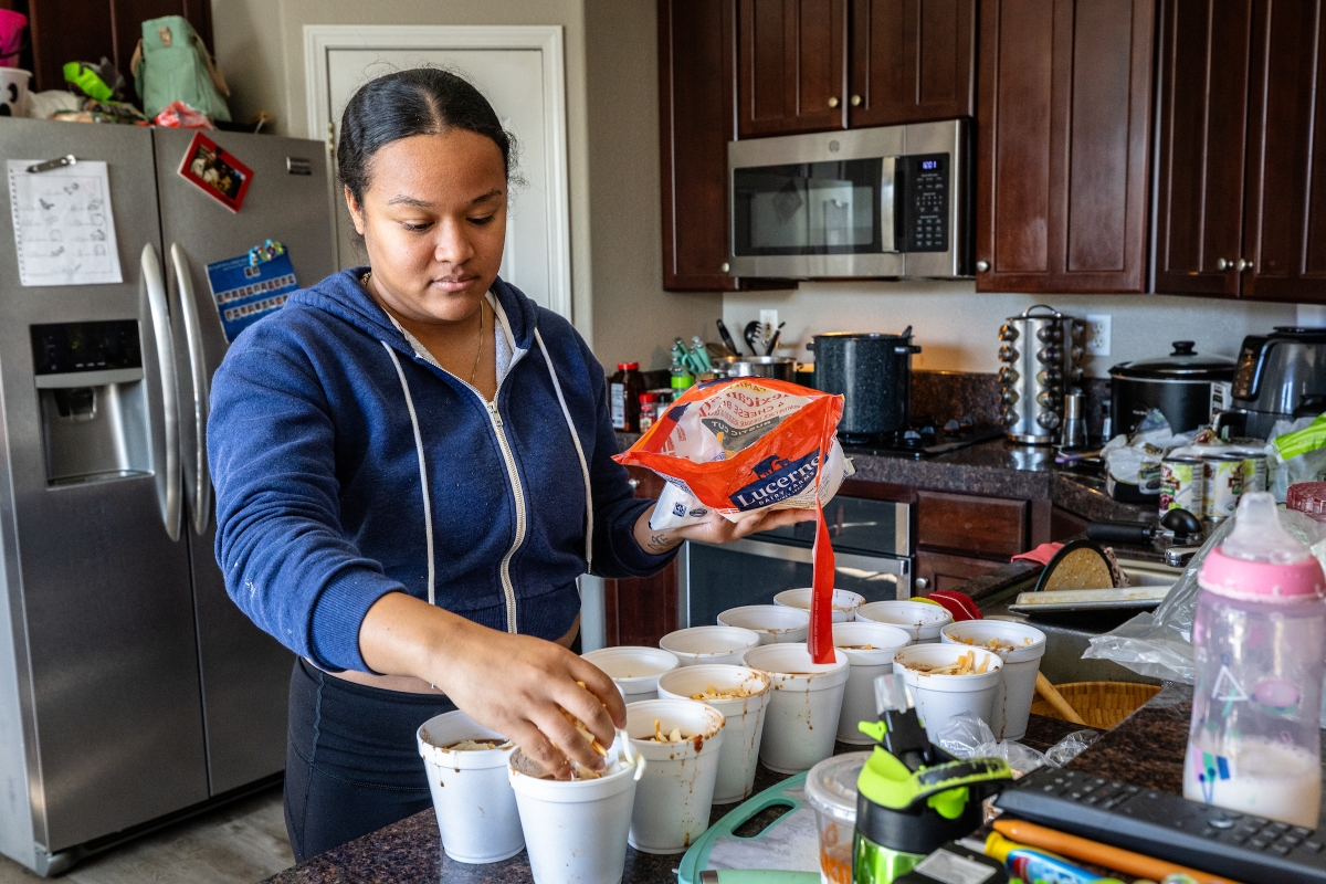 Woman adding cheese to styrofoam cups of chili