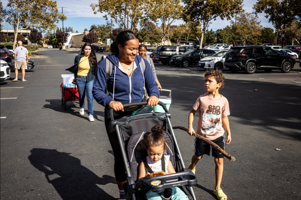 Woman walking with child and pushing stroller with toddler in it
