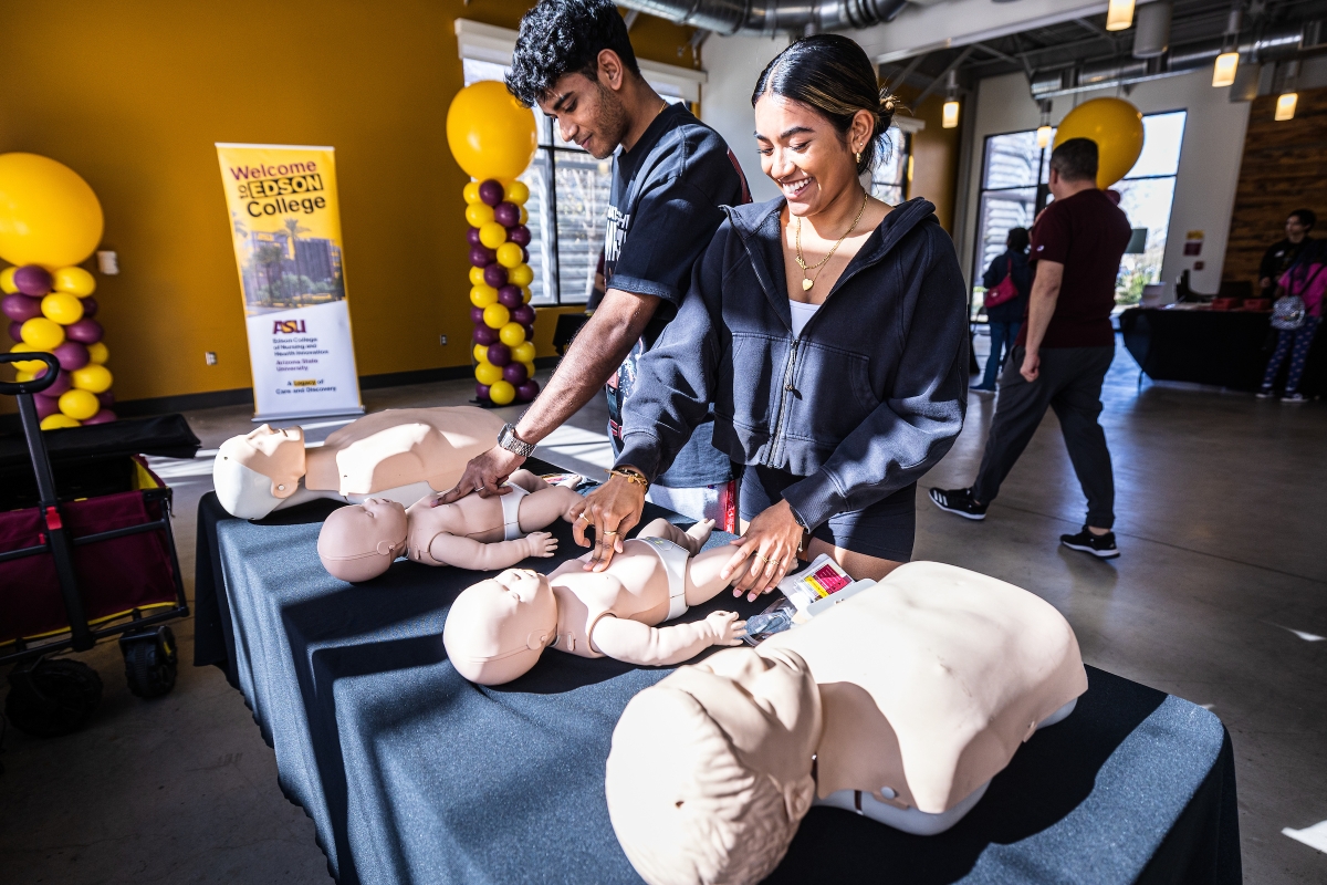 Two college students simulating CPR on test dummies