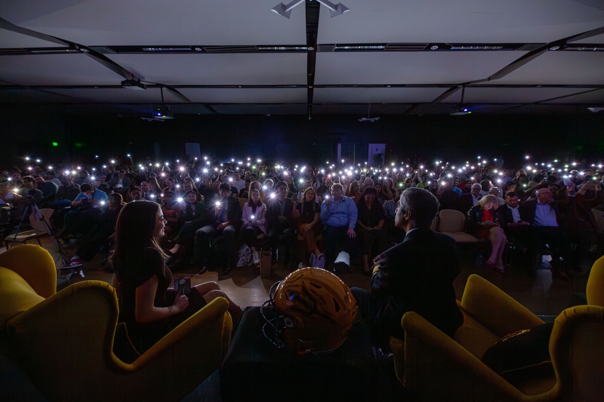 Audience members holding up phone flashlights in the dark