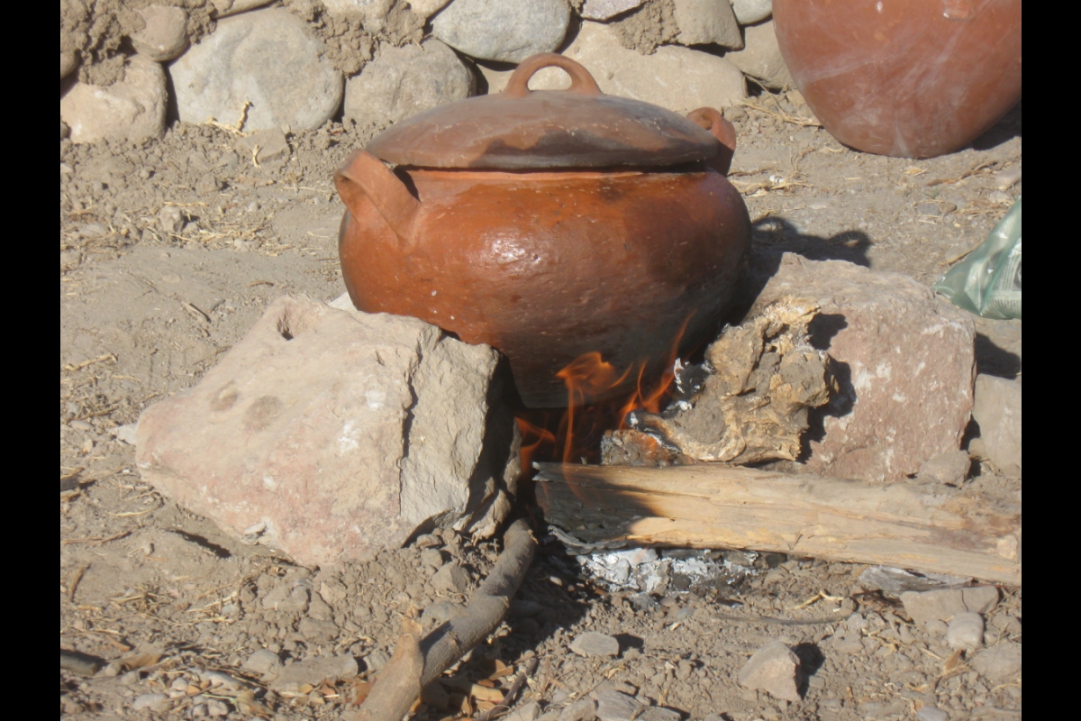 Vessel called olla with lid sitting amidst rocks and dirt.