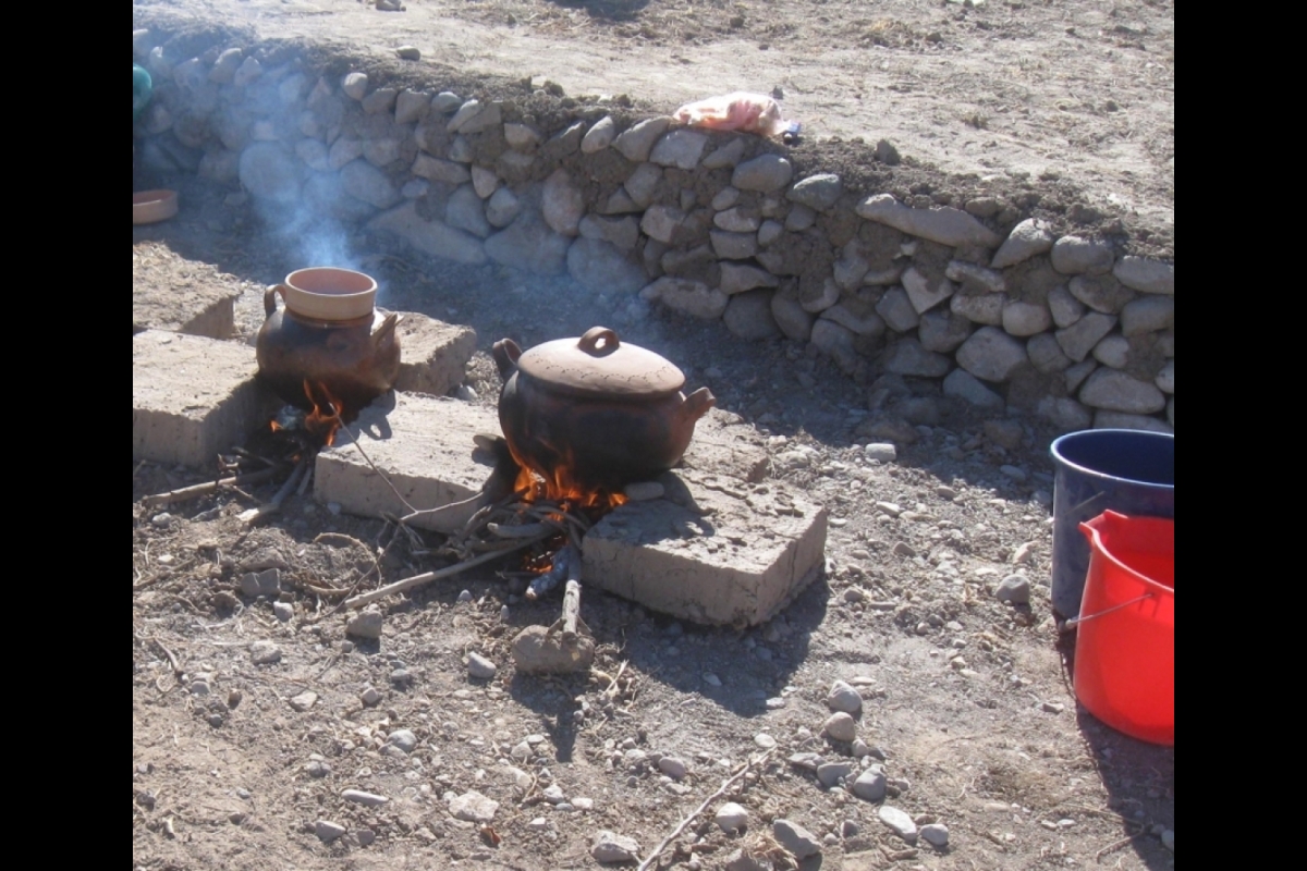 A pot sits above a fire in the dirt.