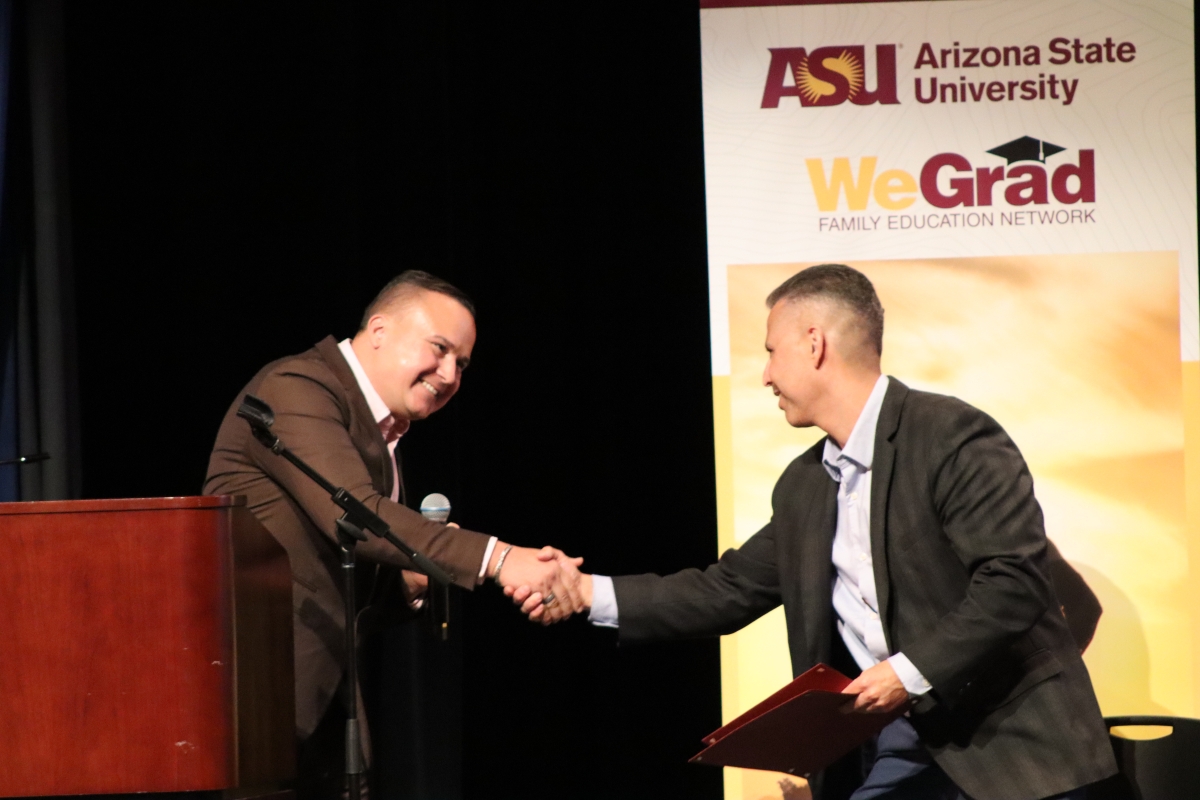 Two men shake hands on stage.