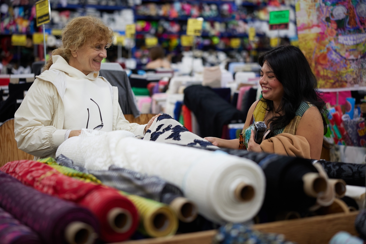 Two people smiling while looking at fabric.