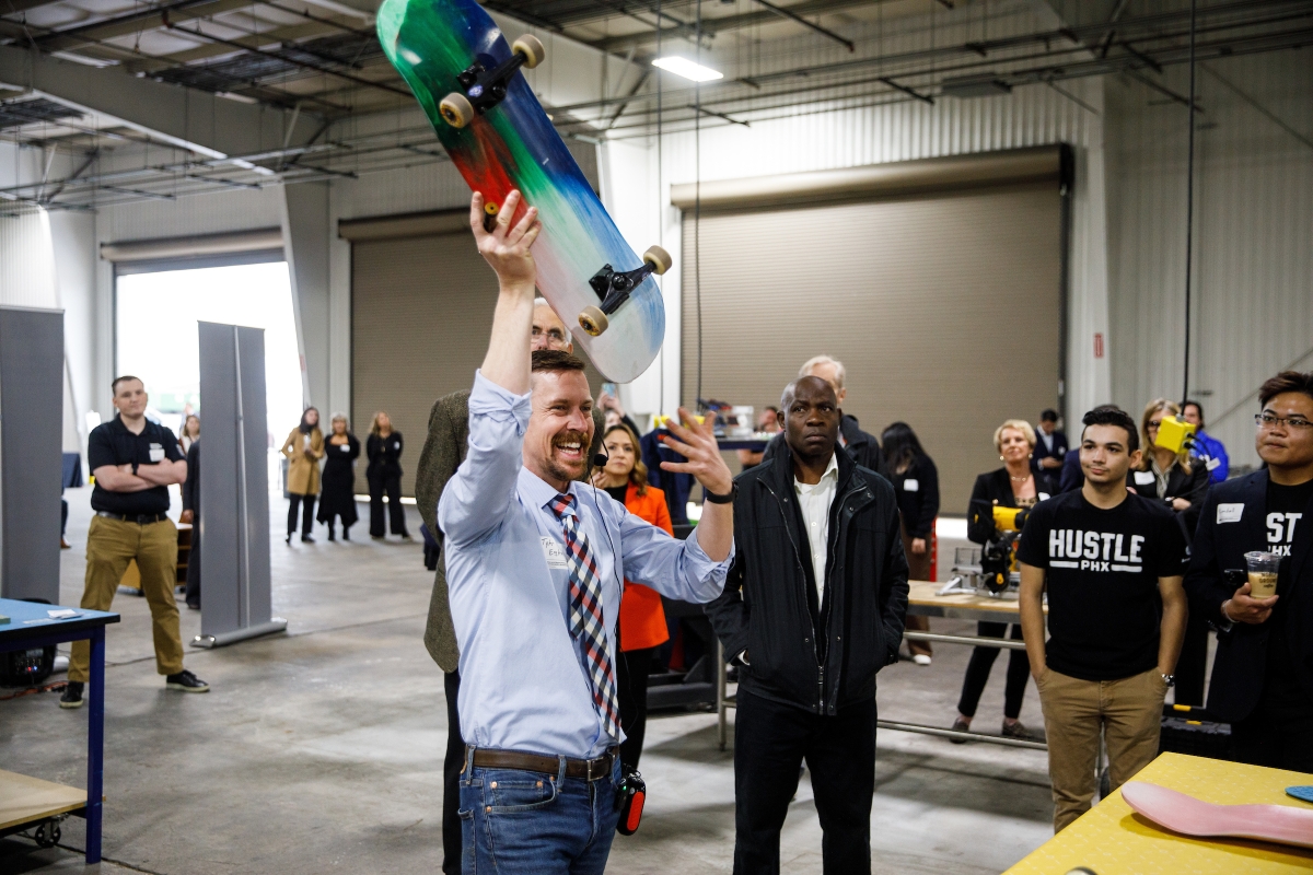 Eglen holds up a colorful plastic skateboard during a tour of the facility.