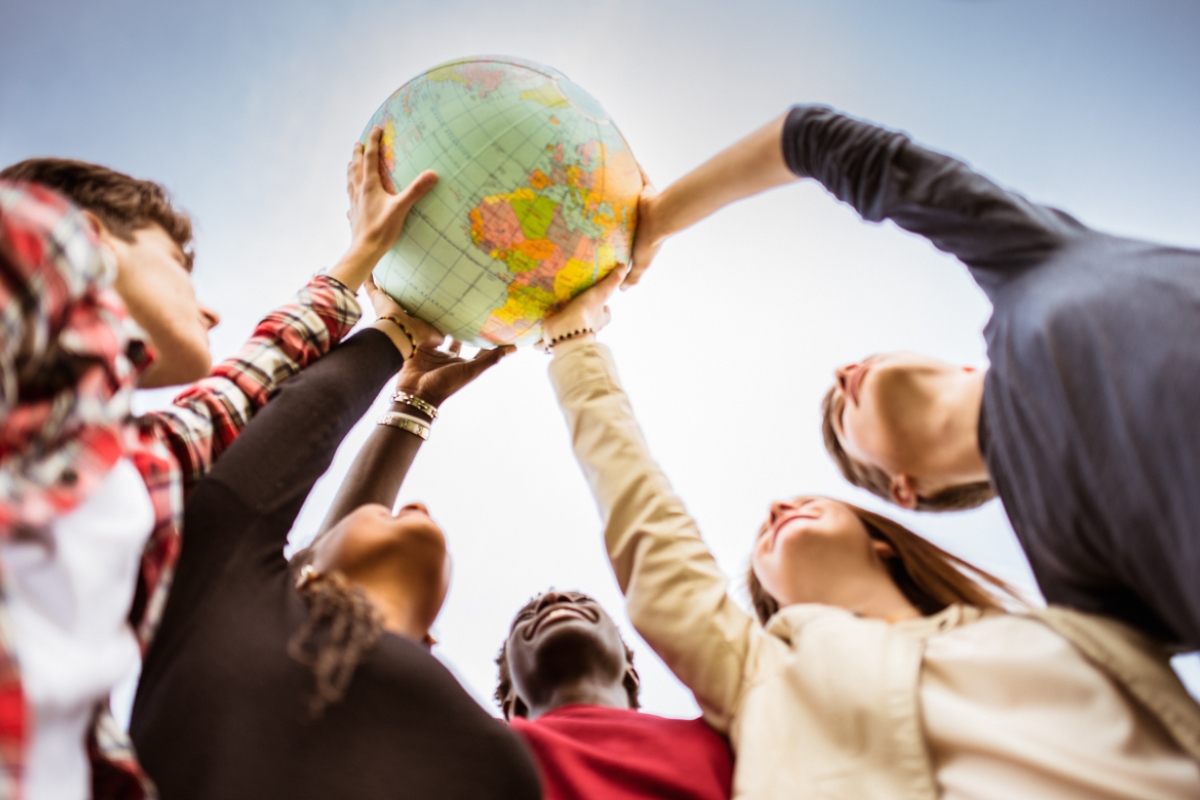 A group of people hold a globe aloft