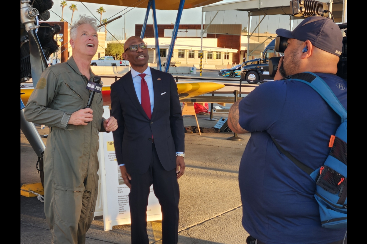 ASU Executive Vice President and Chief Operating Officer Chris Howard and FOX 10 Weather Anchor Cory McCloskey watch a vintage aircraft perform during a live interview, Friday evening, March 22.