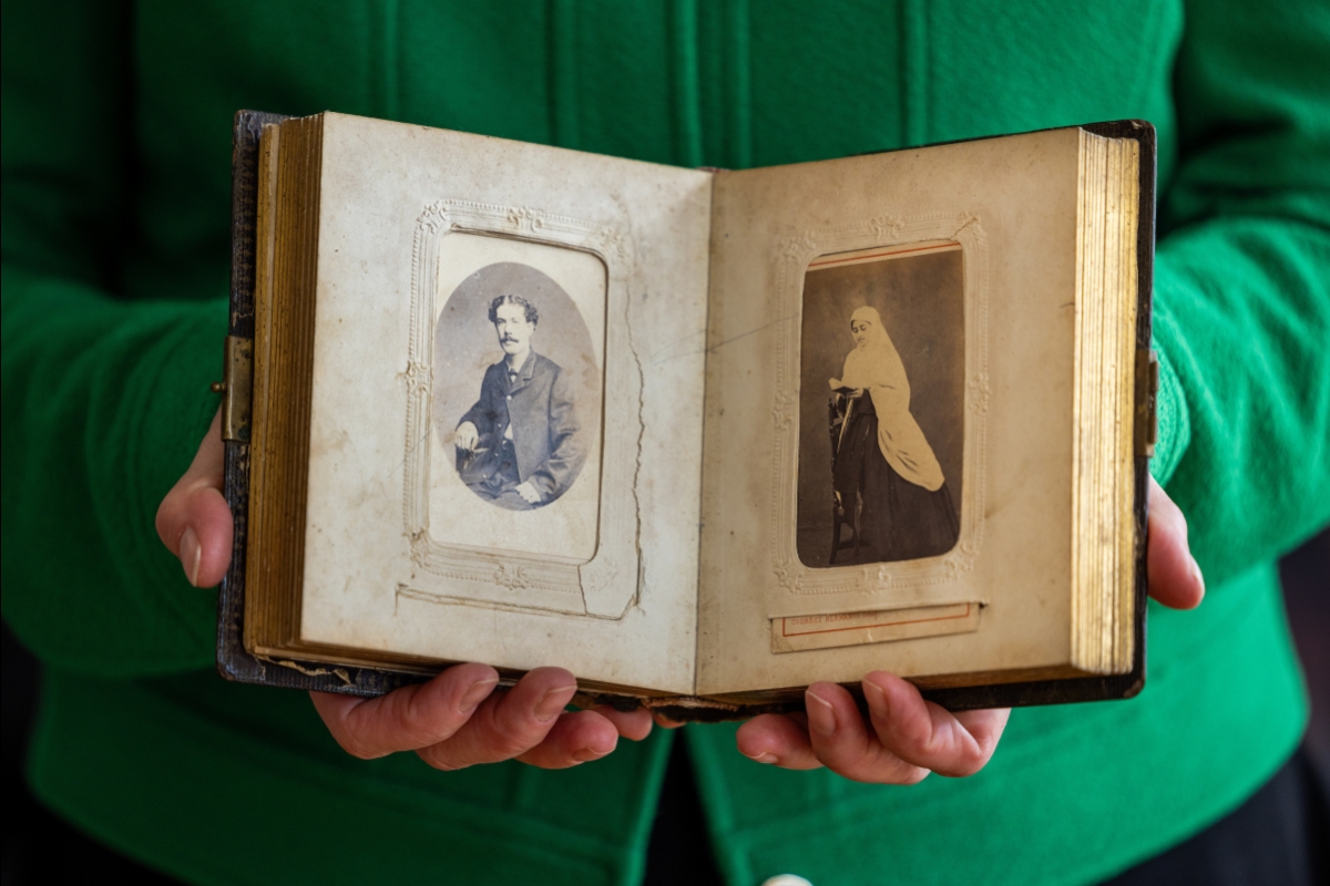 Woman holding antique scrapbook with old photos
