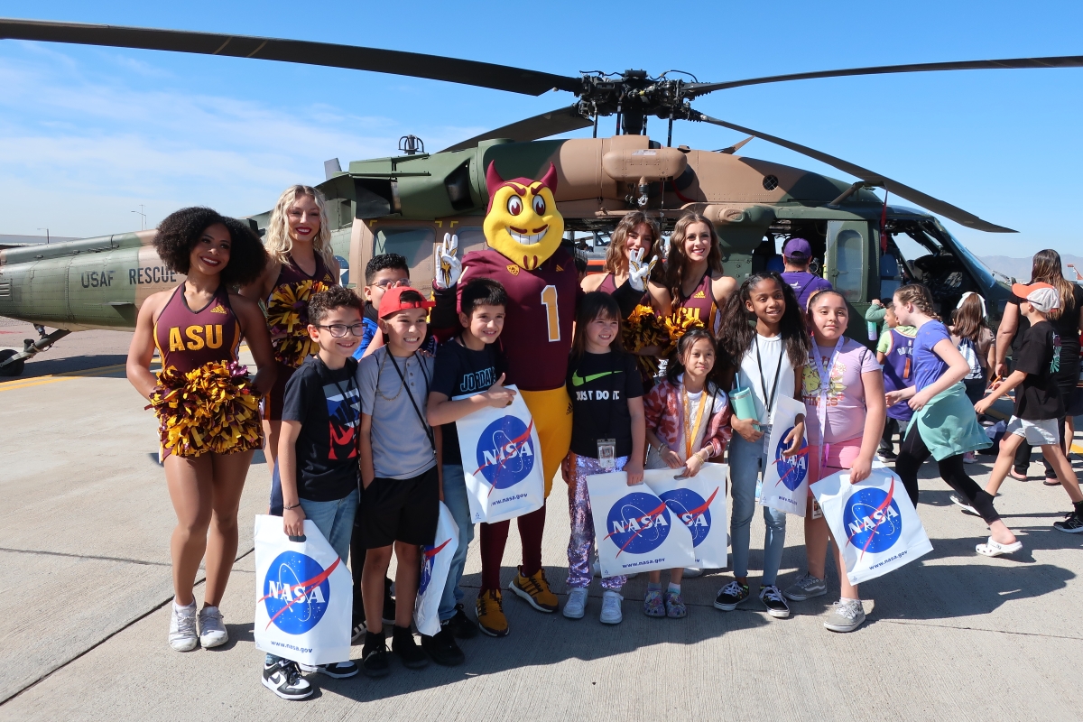  Sparky the Sun Devil and ASU Spirit Squad members pose for a photograph in front of an Air Force HH-60 Pave Hawk with a group of school children on Friday, March 22, at Luke Air Force Base.