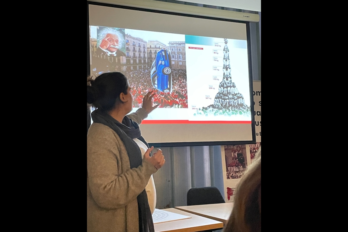 Woman points to an image of a car and a human tower on a projector screen 