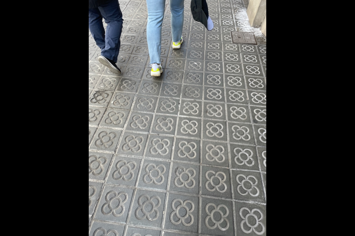 Downward view of people's legs as they walk on tile-lined streets