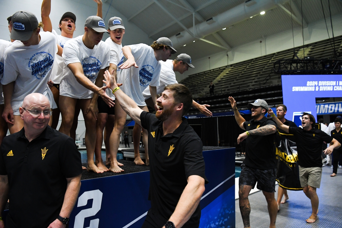 Coaches slap high-fives with swimmers up on a stage