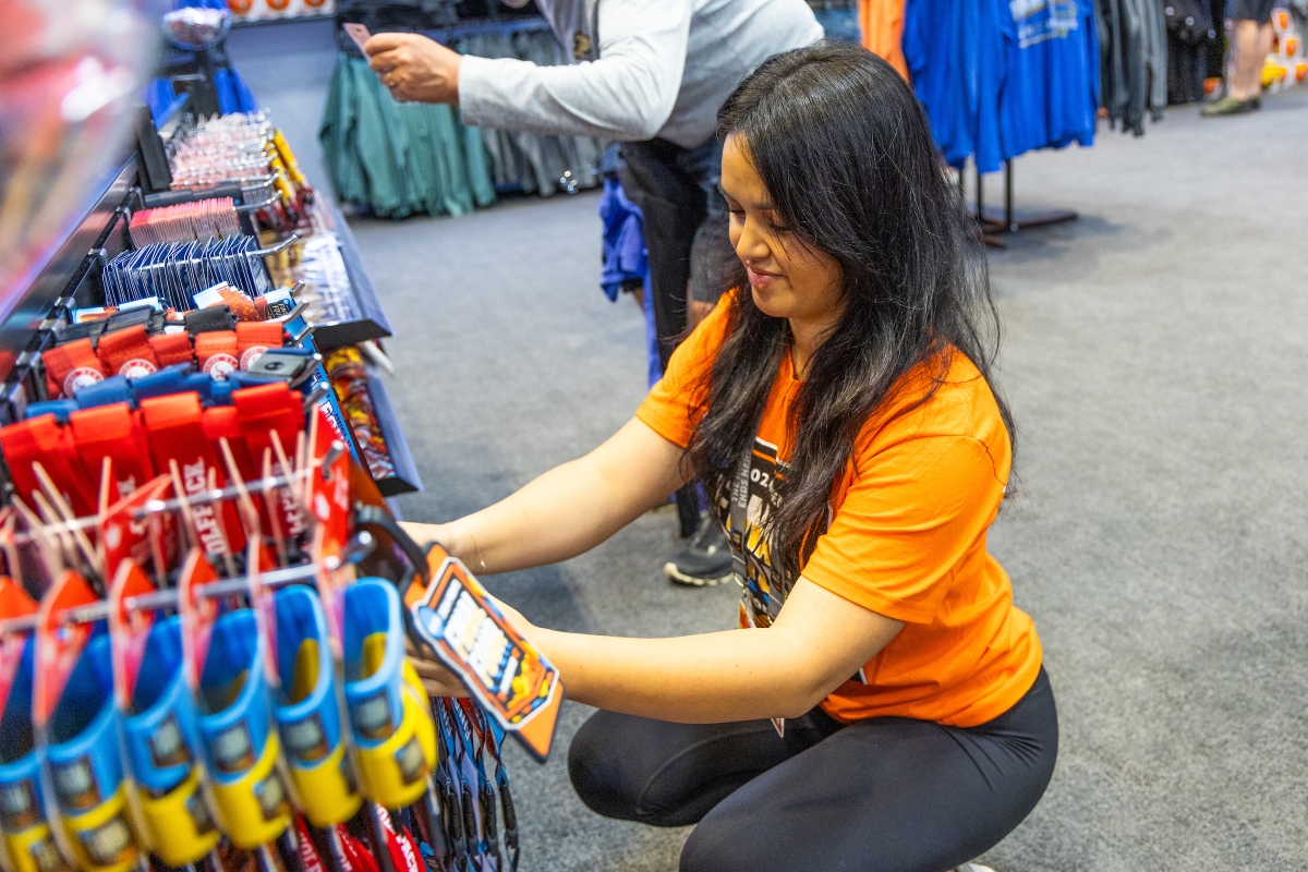 A young woman restocks NCAA Final Four merchandise on hooks.