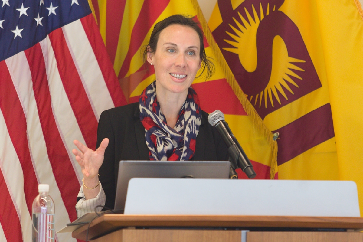 Kathleen Stevens speaking at a lectern, backed by U.S. and ASU flags