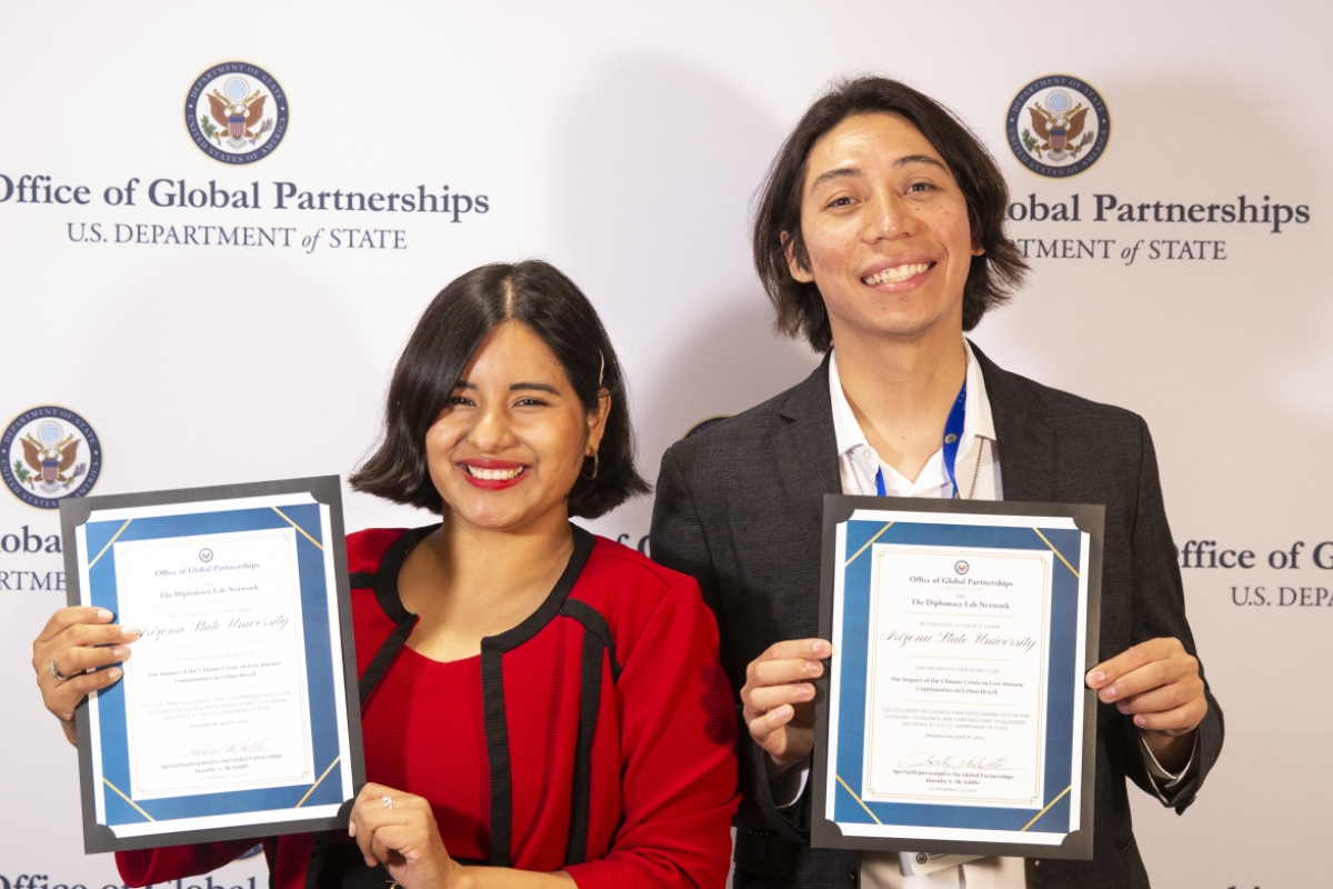 A female and male student proudly hold their certificates of achievement for participating in the Diplomacy Lab Fair. 