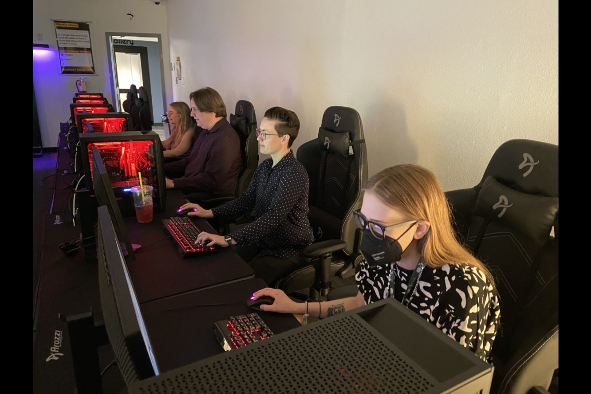 A row of adults sitting at gaming computers in black gaming chairs. 