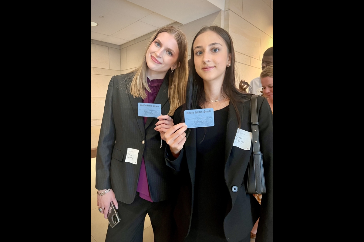 Two Diplomacy Lab students (females) display their ticket to enter the U.S. Senate Chamber while in session.
