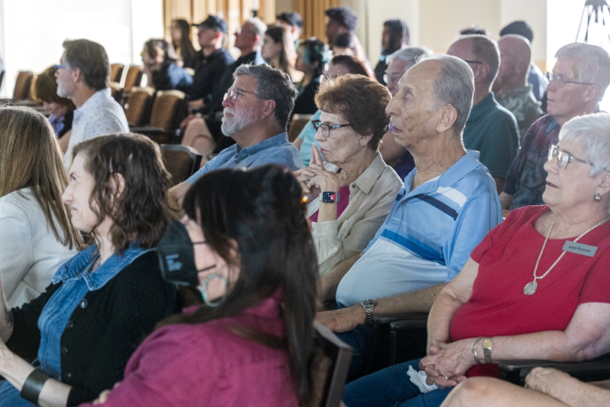 Intergenerational audience looks on to event presentations and performances