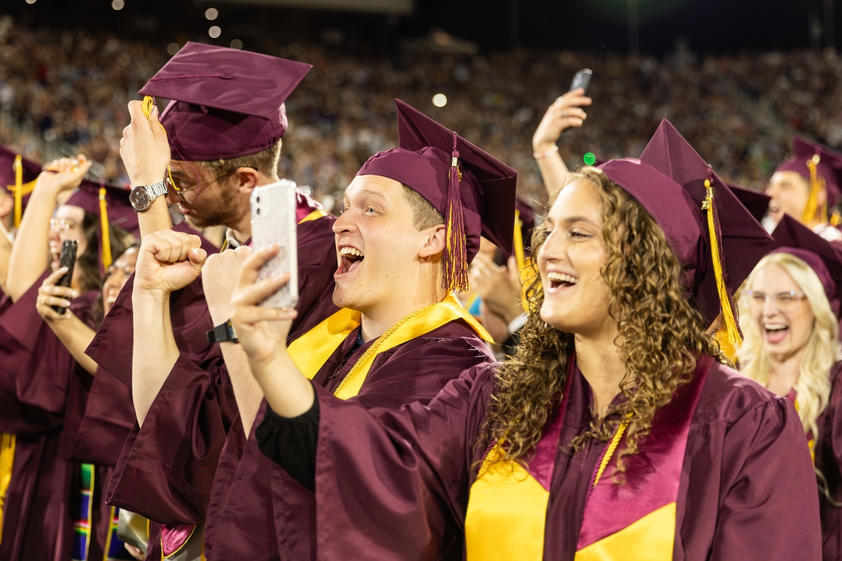 ASU graduates shouting and recording ceremony on phone during commencement