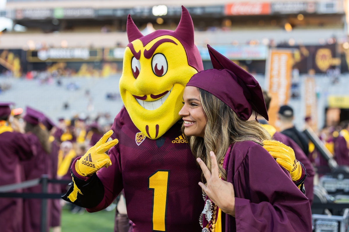 ASU graduate poses with Sparky mascot for a photo