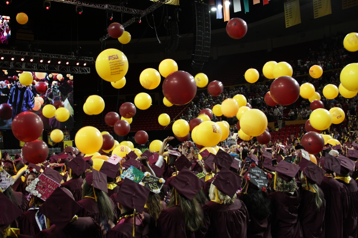 Graduates catch and toss balloons falling from rafters