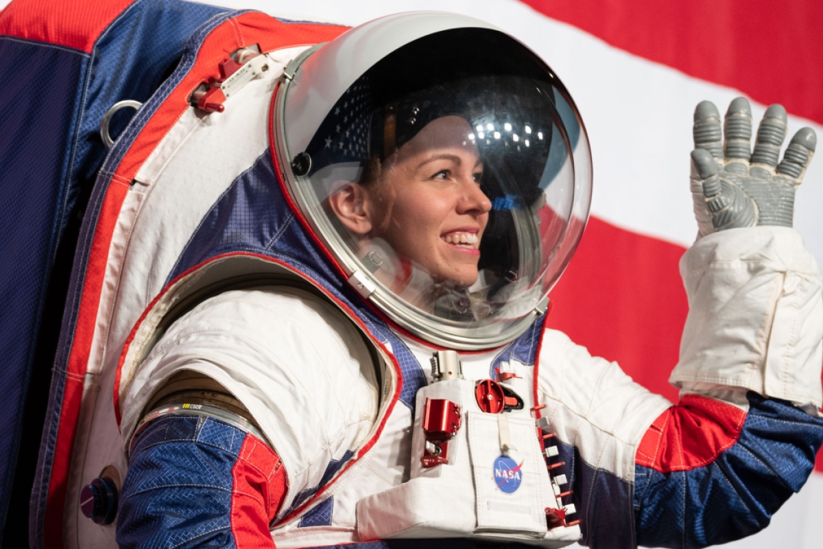 A woman wearing a spacesuit waving