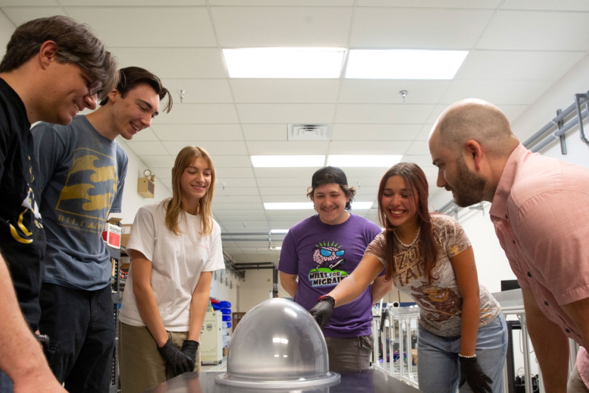 A group of people examines a spacesuit helmet bubble