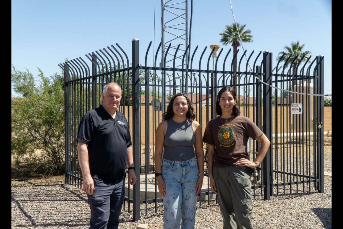 Three people standing outside near a fence in Phoenix.