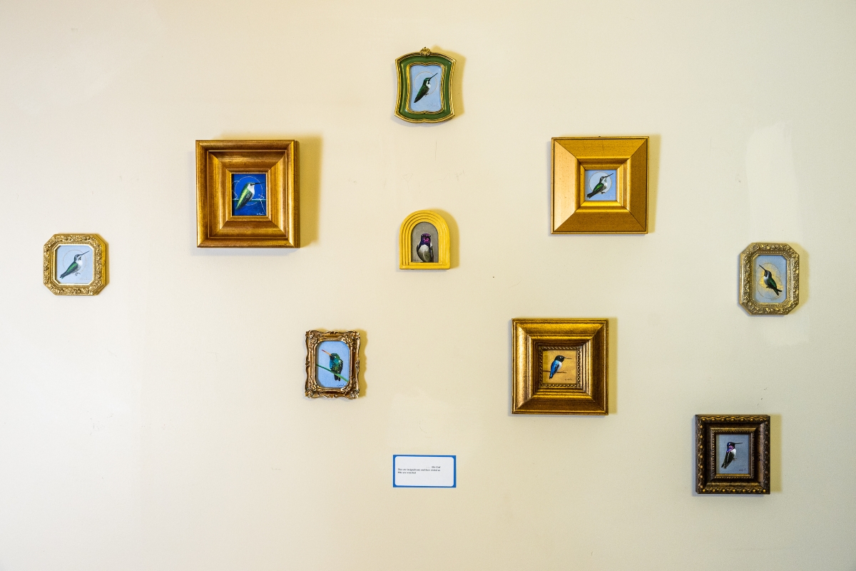 A collection of tiny paintings together on a wall.