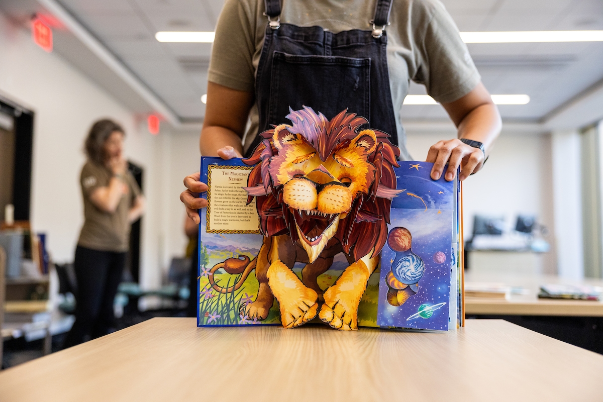 Hands display a movable book opened to a page featuring a lion.