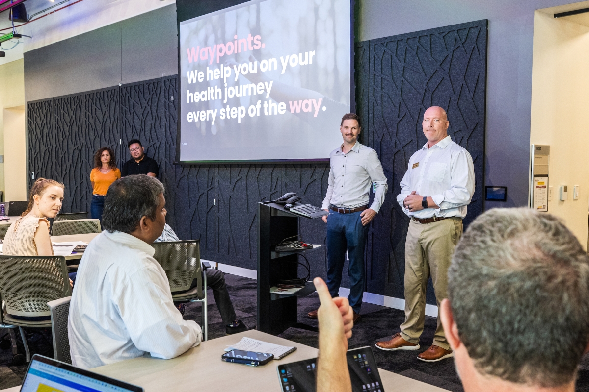 Two people giving a powerpoint presentation with someone from the audience giving a heads up