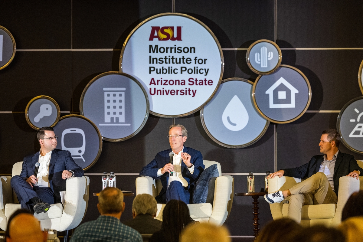 Three people sitting on chairs on stage for panel