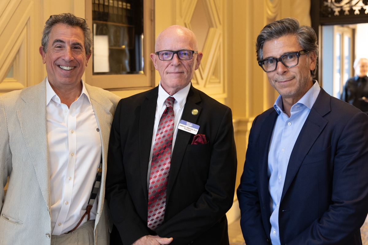 Three men in suit jackets pose for photo