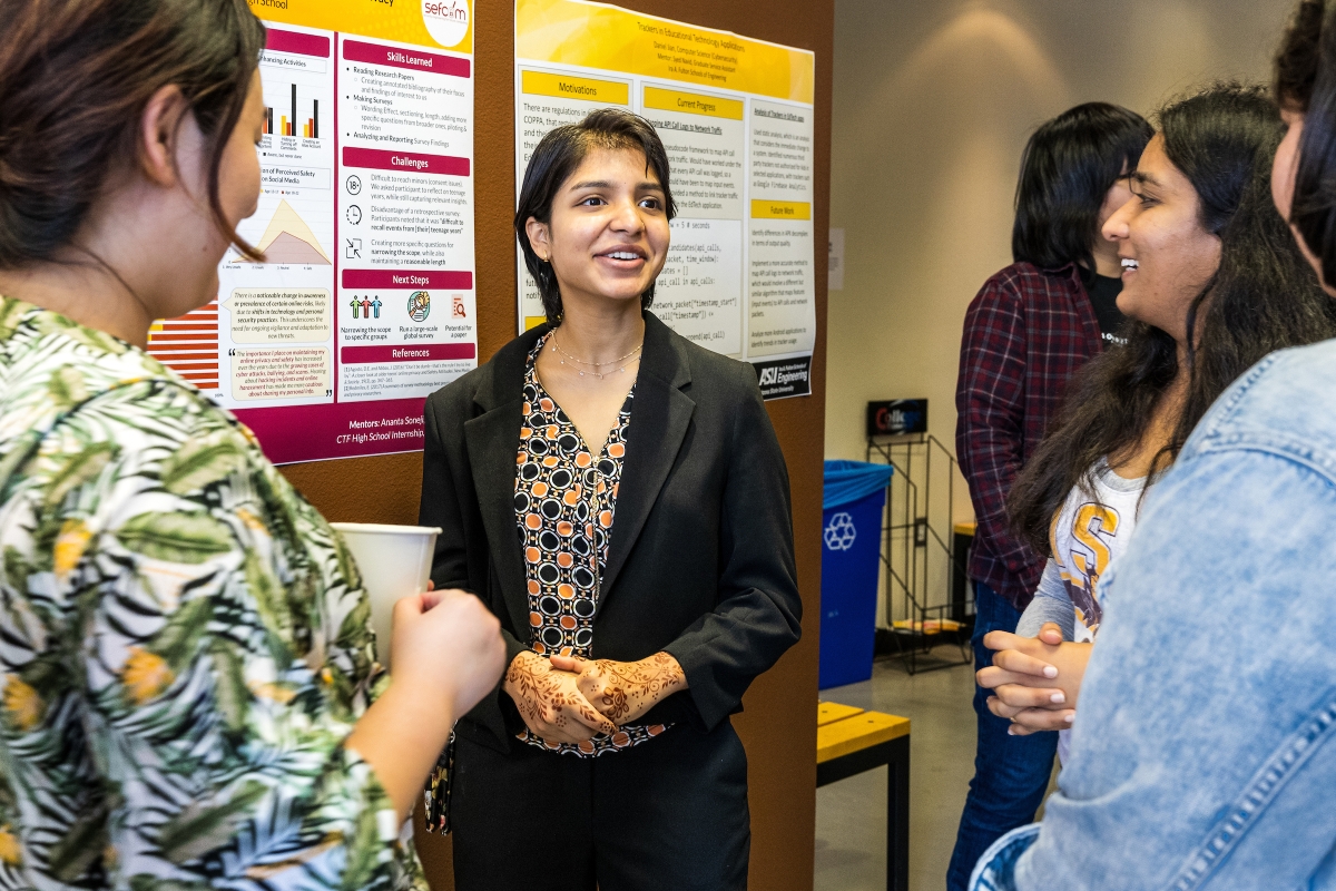 High school student talking with attendees of a research poster session