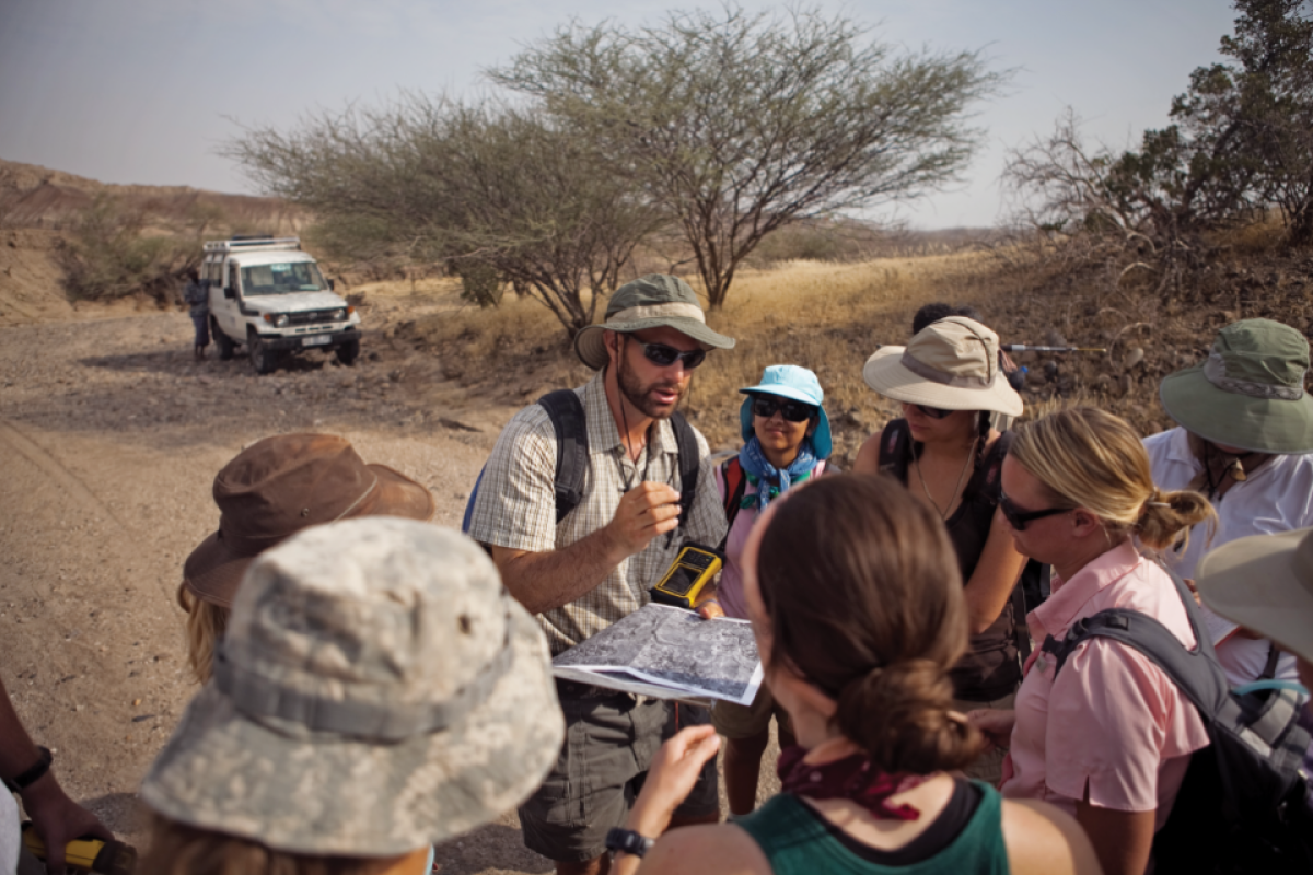 Man leads group of people on field outing in Ethiopia