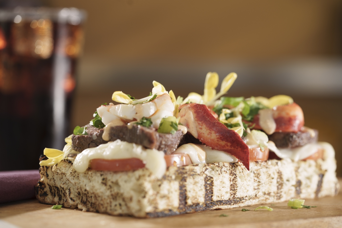 Closeup of a flatbread with lobster and steak on top