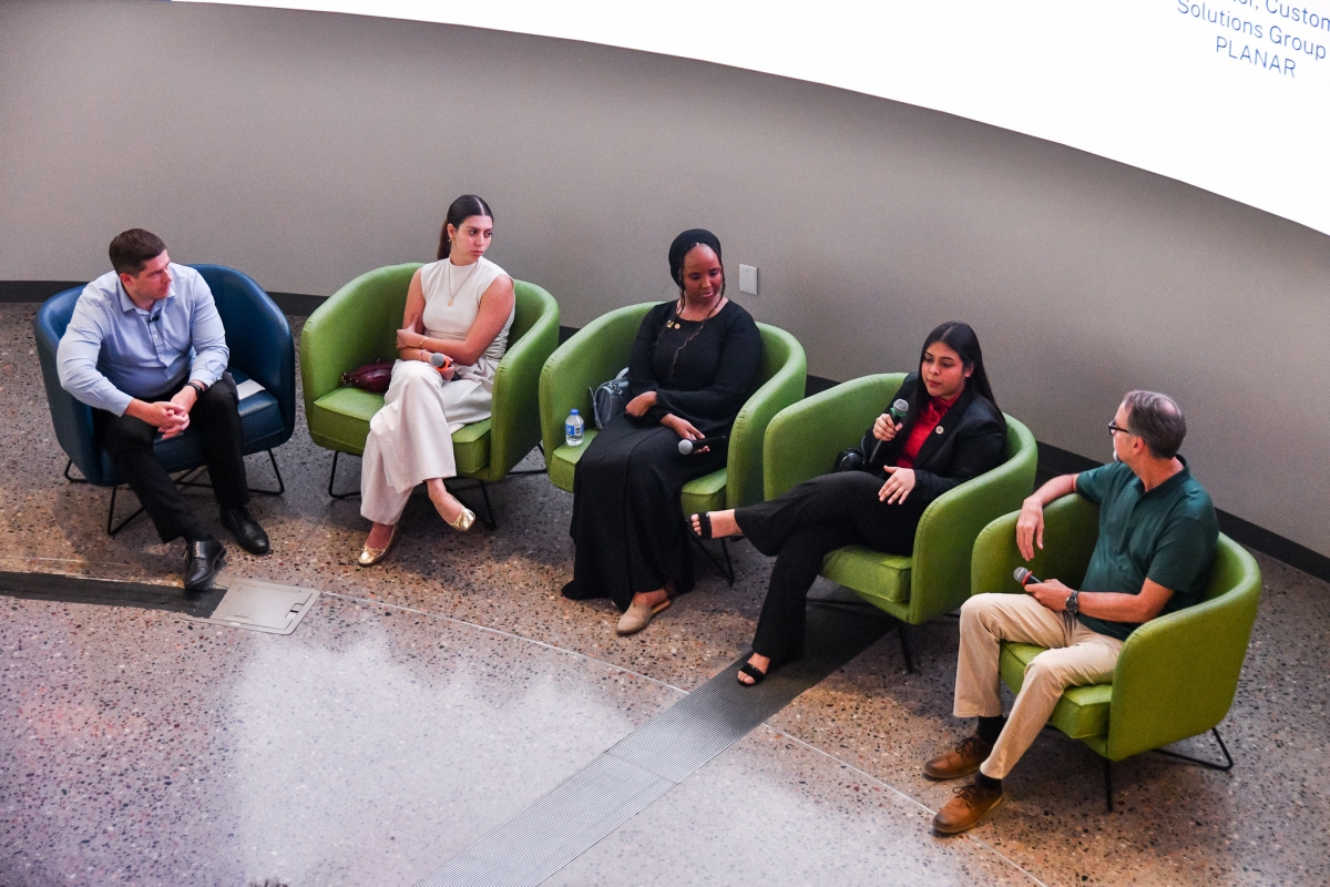 People seated in chairs listening to one person with a microphone.