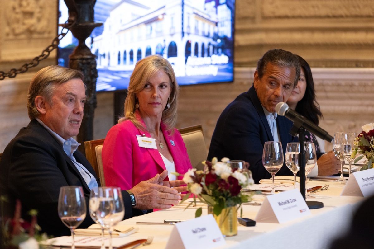 Three people sitting at long dinner table with microphones