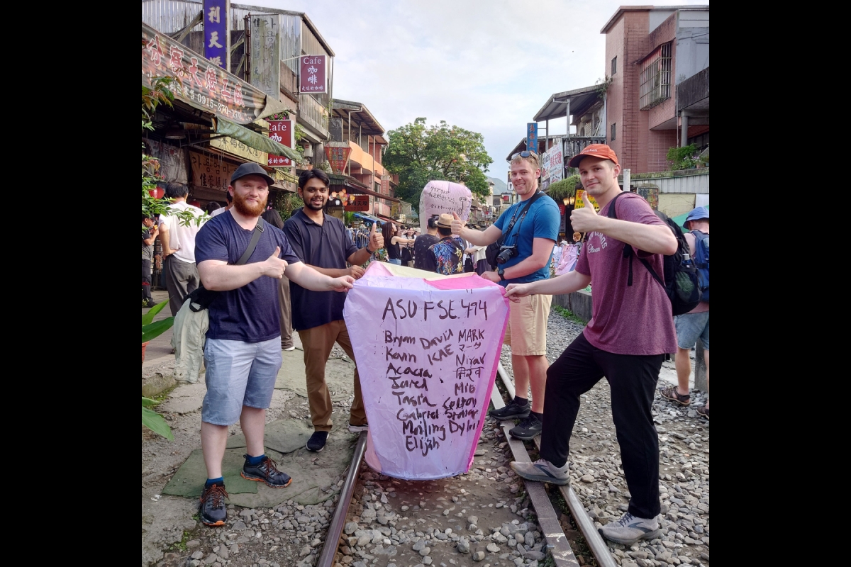 Students hold a sign with the names of all the 2024 History and Technology of Microelectronics - Taiwan study abroad experience participants at Shifen Old Street in Taiwan.